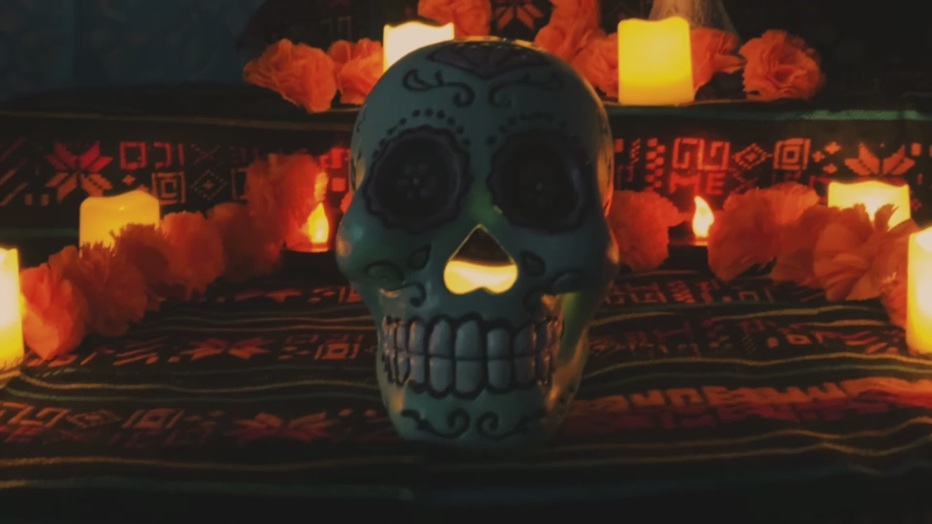 Load video: Welcome video for Catrina Salsas &amp; Carnes featuring a Day of the Dead skull surrounded by candles and a traditional Mexican altar setup.